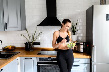 Genç bir kadın mutfakta namaz kılıyor.