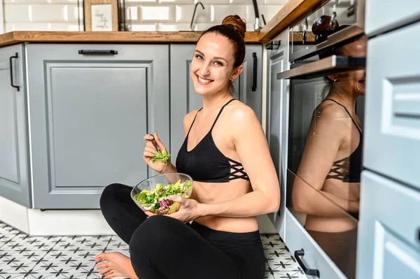 Giovane donna mangia salat in cucina — Foto Stock