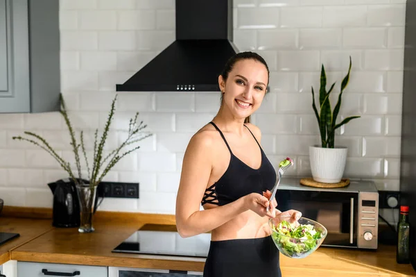 Giovane donna mangia salat in cucina — Foto Stock