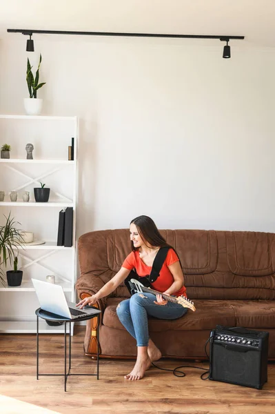 Una donna impara a suonare la chitarra elettrica a casa — Foto Stock