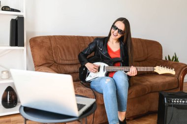 Bir kadın evde elektro gitar çalmayı öğrenir.