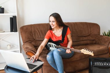 Bir kadın evde elektro gitar çalmayı öğrenir.
