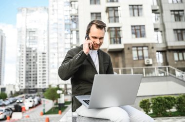 Şehirde dizüstü bilgisayarı olan genç bir adam.,