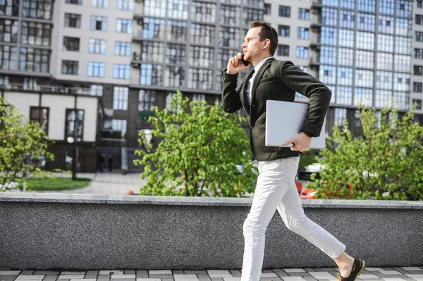 Un tipo con un portátil en casual inteligente es tarde — Foto de Stock