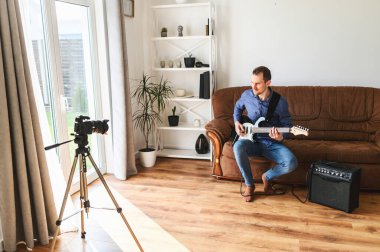 Bir adam elektro gitar çalmayı videoya kaydediyor.