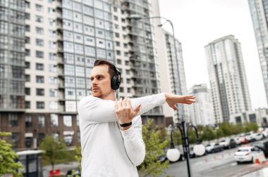 Spor kıyafetli genç adam dışarıda antrenman yapıyor.