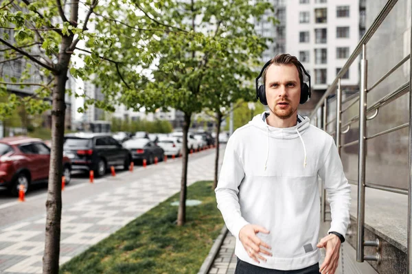 Young man in sportswear with headphones runs