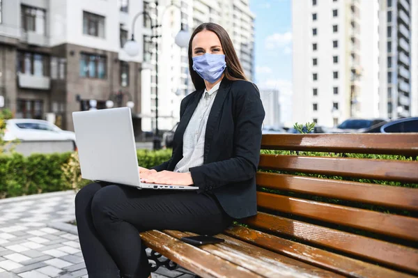 밖에 랩탑을 가지고 있는 의료용 마스크를 쓴 여자 — 스톡 사진