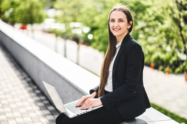 En ung kvinna som använder laptop för arbete utomhus — Stockfoto