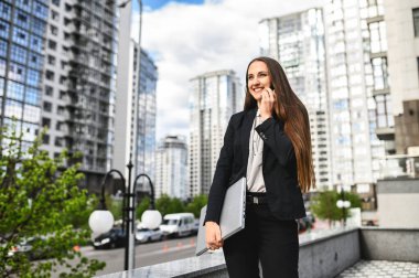 Bilgisayarlı genç bir kadın telefonda konuşuyor.