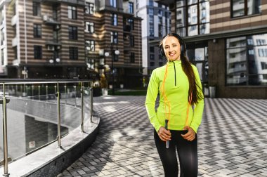 Parlak spor kıyafetli kadın dışarıda duruyor.