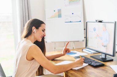 Genç bir kadın bilgisayar ekranında webinar izliyor.