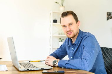 Yakışıklı adam iş için dizüstü bilgisayar kullanıyor.