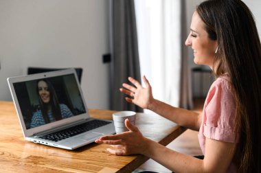 Bilgisayarı video görüşmesi için kullanan genç bir kadın, yakınlaştır