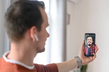 Bir adam video görüşmesi için akıllı telefon kullanıyor, zoom