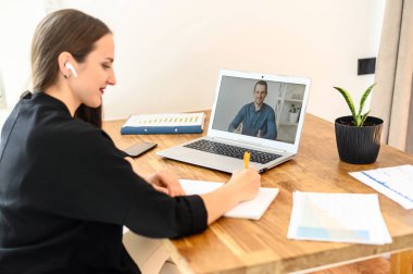 Genç bir kadın dizüstü bilgisayarda Webinar izliyor.