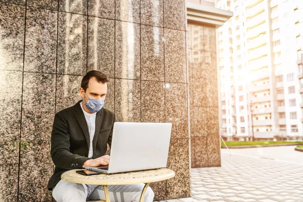 Людина в захисній масці працює з ноутбуком — стокове фото