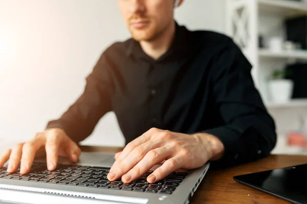 Un gars en chemise noire utilisant un ordinateur portable pour le travail — Photo