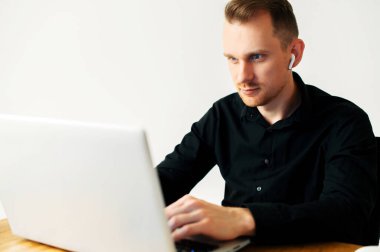 İş için laptop kullanan siyah tişörtlü bir adam.