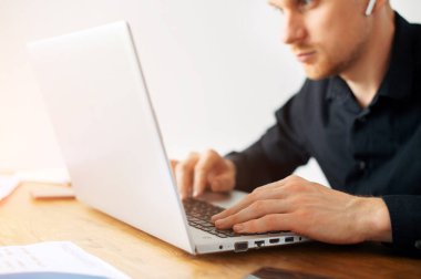 İş için laptop kullanan siyah tişörtlü bir adam.