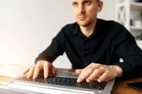 Парень в черной рубашке, использующий ноутбук для работы — стоковое фото