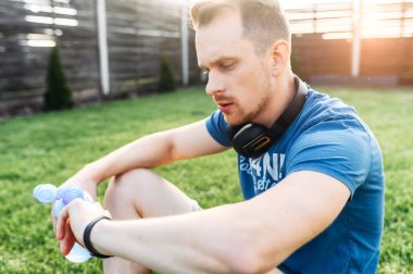 Spor kıyafetleri giyen bir adam kalp atışlarını kontrol eder.