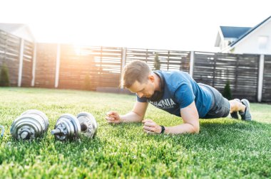 Spor kıyafetli bir adam kalas egzersizi yapıyor.