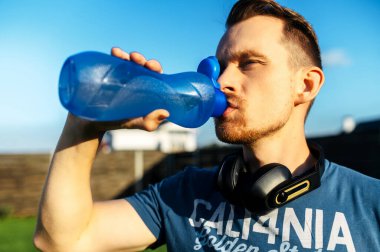 Adam dışarıda çalışırken susuzluğunu gideriyor.