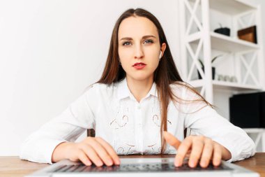 Resmi beyaz gömlekli genç bir kadının webcam görüntüsü.