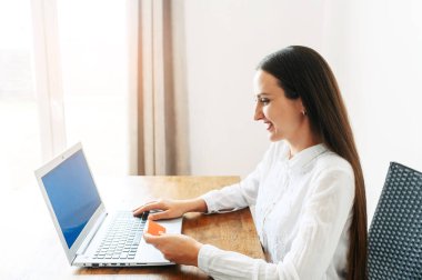 Laptop kullanan kredi kartı olan genç bir kadın.