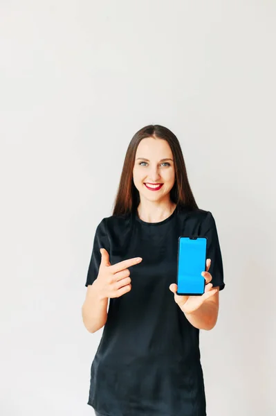 Chica joven en camiseta negra con un teléfono inteligente — Foto de Stock