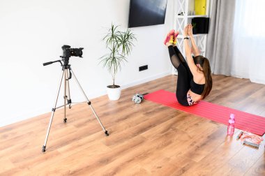 Genç bir kadın spor videoları kaydediyor.