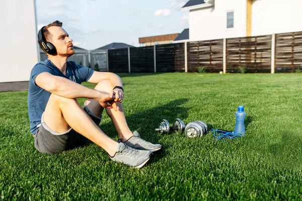 A guy in sportswear sits on the lawn