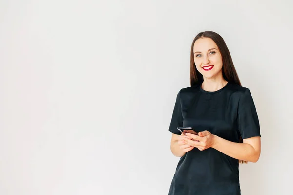 Chica joven en camiseta negra con un teléfono inteligente — Foto de Stock