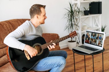 Adam online izleyicilere akustik gitar çalıyor.