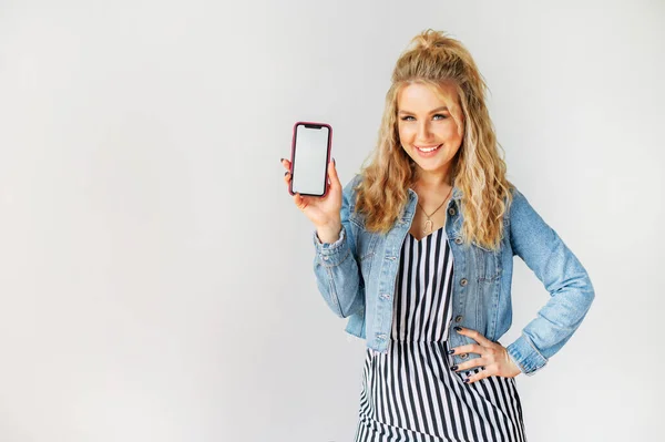 Atractiva joven mujer muestra una pantalla de teléfono en blanco — Foto de Stock