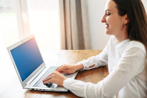 Eine junge Frau in schickem lässigem weißem Hemd mit Laptop — Stockfoto