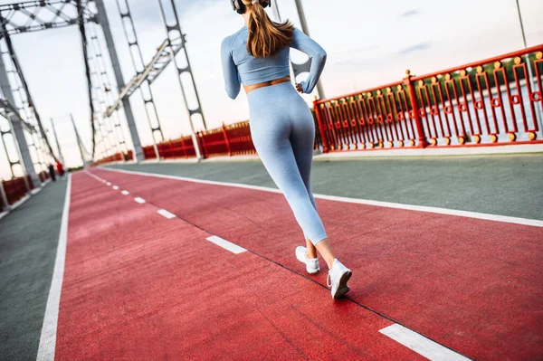 Genç kadın şehir köprüsünde koşuyor.