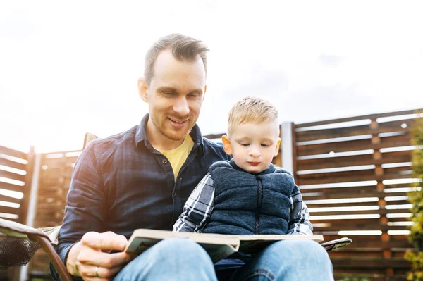 Father and toddler son read a book together