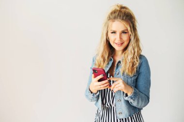 Elinde akıllı telefon olan sarışın bir kadın.