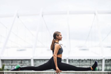 Güzel esnek kız dışarıda sicimin üzerinde oturuyor.