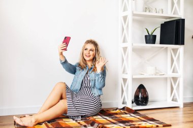 Video görüşmesi için telefon kullanan genç bir kadın.