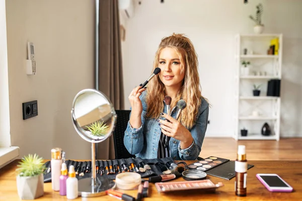 Jeune femme regarde miroir et faire du maquillage — Photo