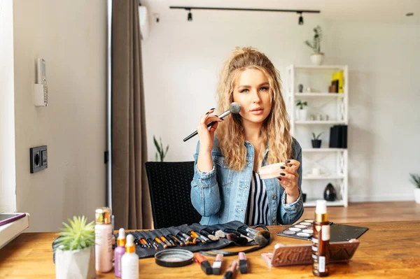 Young woman looks at mirror and doing makeup — Stock Photo, Image