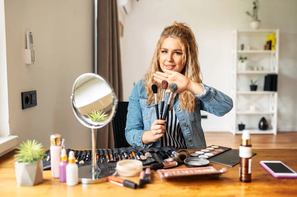 Young woman looks at mirror and doing makeup — Stock Photo, Image