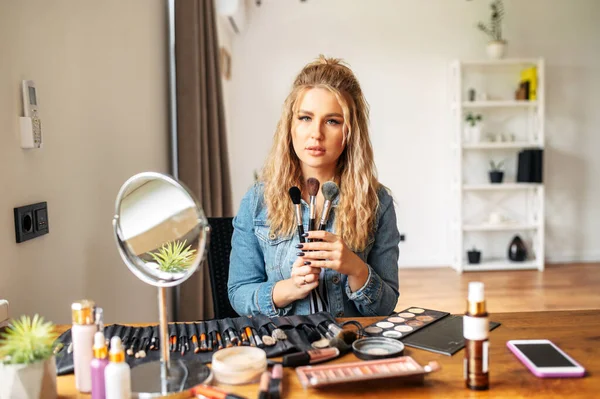 Young woman looks at mirror and doing makeup — Stock Photo, Image