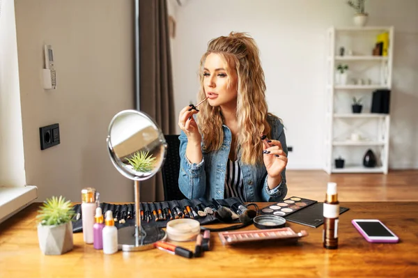 Jeune femme regarde miroir et faire du maquillage — Photo