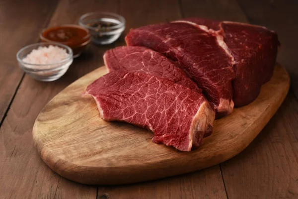 Angus beef meat sliced on a wood cutting board.