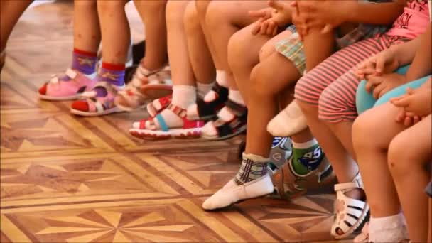 Niños sentados en fila y moviendo los pies — Vídeos de Stock