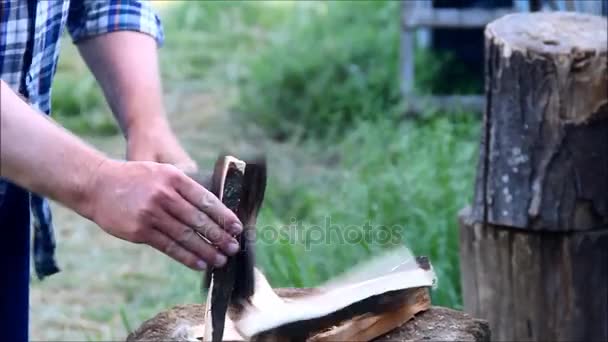 L'uomo divide accuratamente un pezzo di legno in un sottile accendino con un'ascia — Video Stock